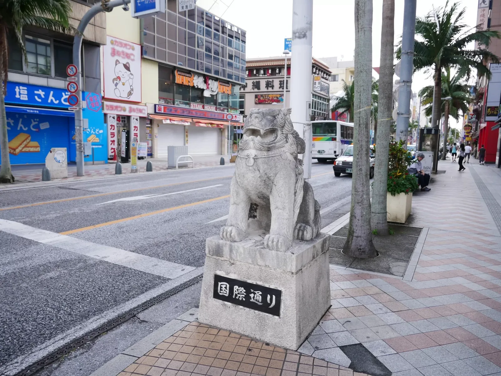 A stone shisa on a plinth marked Kokusai-dori, at the entrance to the street in Naha