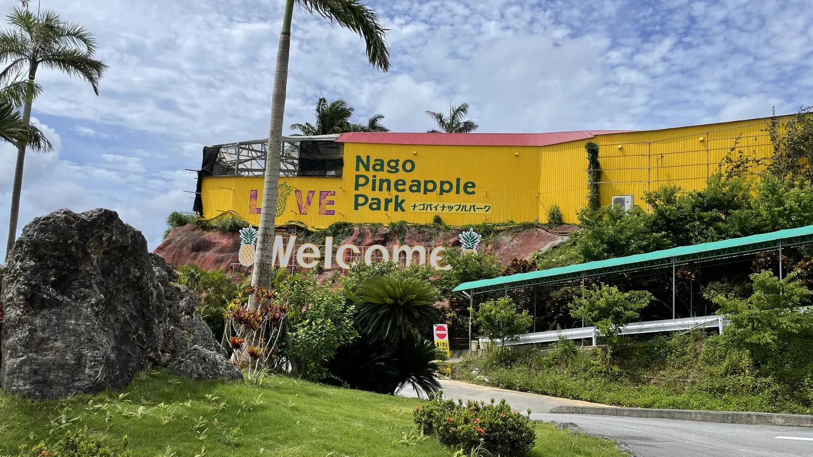 ナゴパイナップルパークの入口。黄色い建物に Nago Pineapple Park と Welcome の看板が出ている