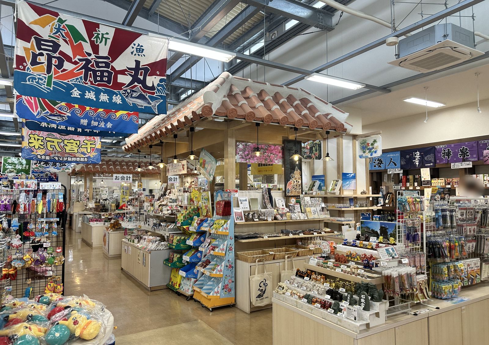 大漁旗と赤瓦の売店が並ぶ、沖縄の道の駅のお土産コーナー