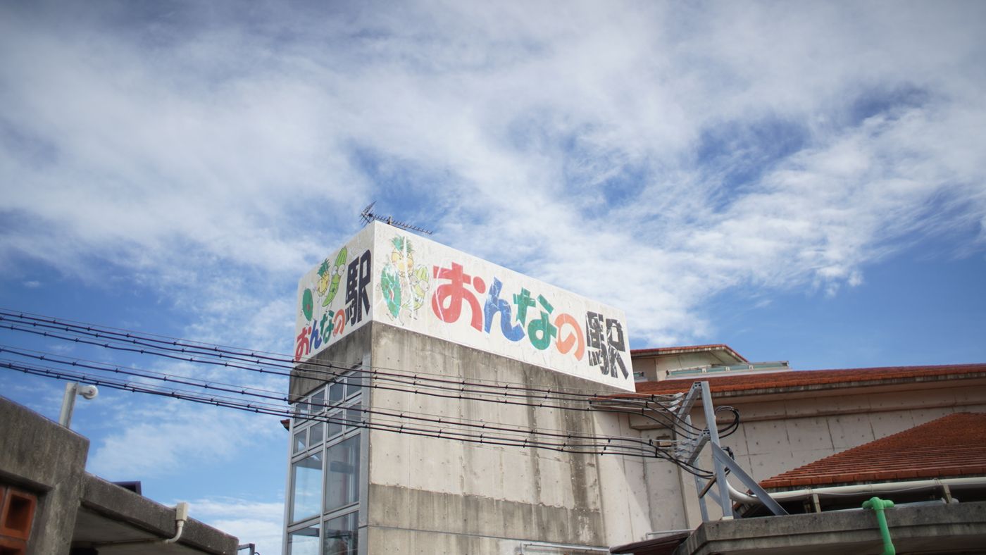 青空に立つ「おんなの駅 なかゆくい市場」の看板