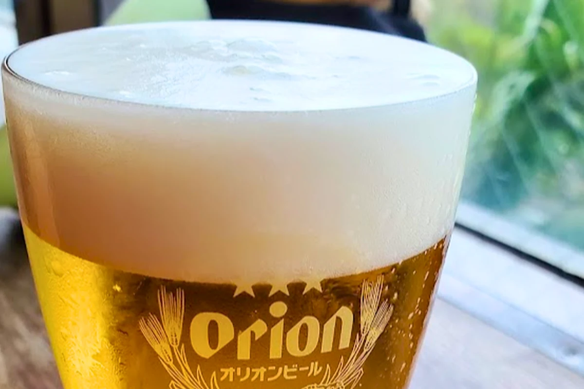 オリオンビールのロゴが入ったグラスに注がれたビール。泡が立ち上がっている