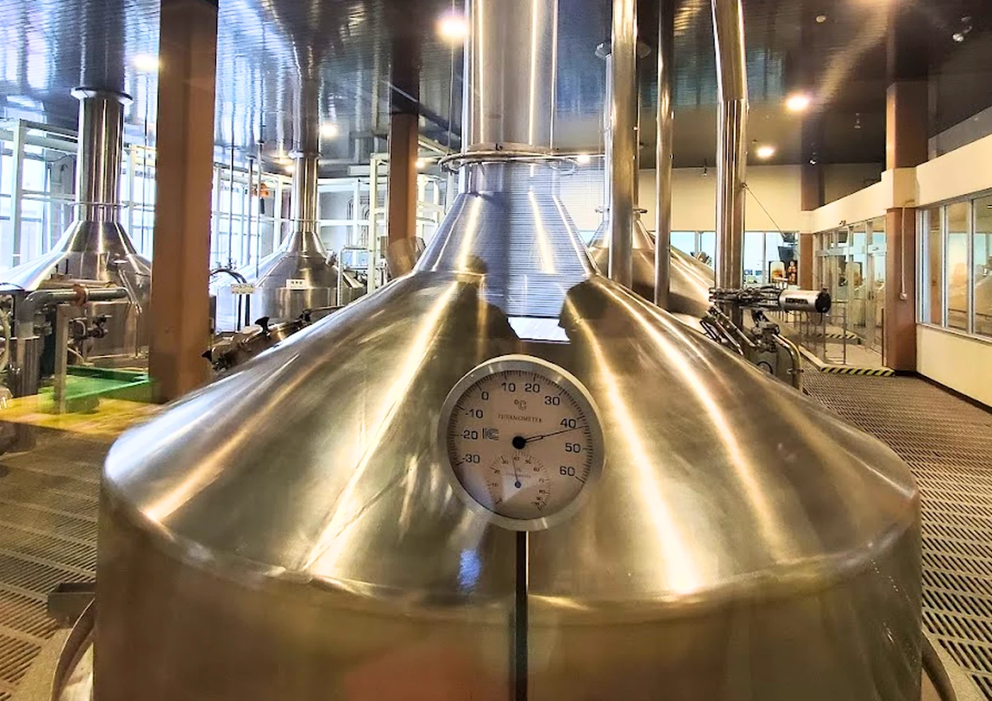 ビール工場の銅色の仕込釜。手前に温度計のついた大きなタンクが並んでいる