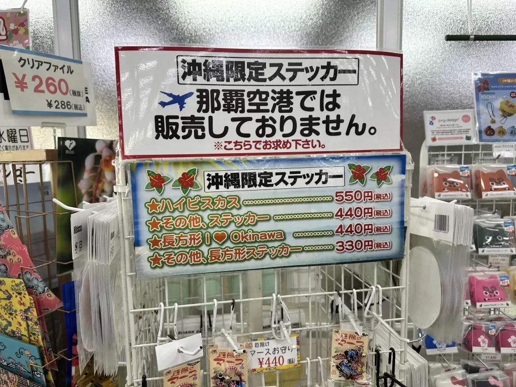 「沖縄限定ステッカー 那覇空港では販売しておりません」と書かれた店頭の掲示と価格表